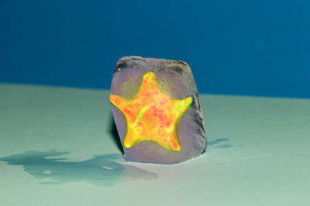 a yellow star in an ice cube on a blue backgroundの写真素材
