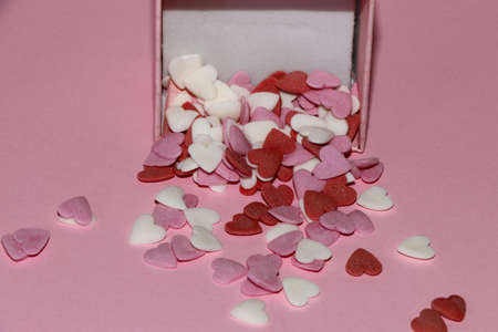 a lot of spilled love pills of hearts from the box on a pink background