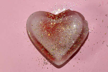damaged heart of ice with glitter on a pink backgroundの写真素材