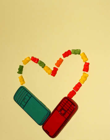 a heart of two old phones and rubber bears on a yellow background