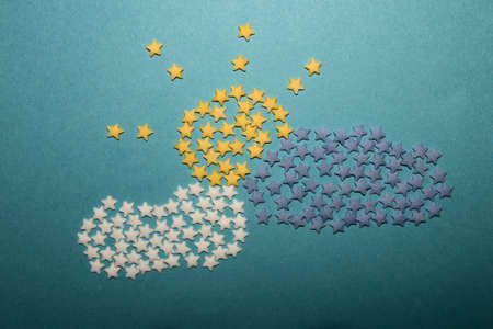 creative concept of the sun behind the clouds made of small stars for decoration on a blue...