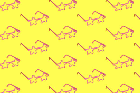 pink star-shaped glasses copied all over the yellow background. relaxed composition spring summer sunny day conceptの写真素材