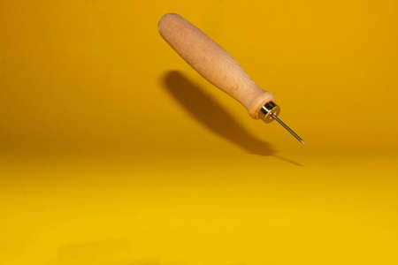awl isolated on a yellow background with its shadow, work tools, copy spaceの写真素材