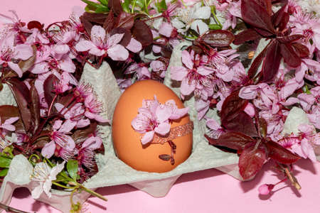 decorated egg in an egg box with lots of flowers, creative spring easter concept, happy holidays