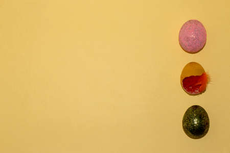 three easter eggs, pink, greensa glitter and yellow shell with orange straw decoration, eggs on the...