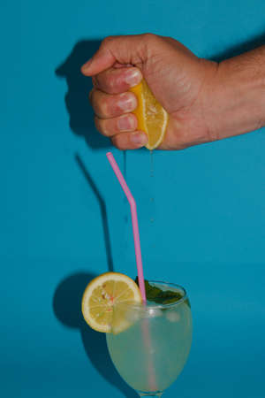 hand squeezing lemon hand squeezing lemon and juice leaking in a nicely decorated glass with lemonade, happy lemonade dayの写真素材