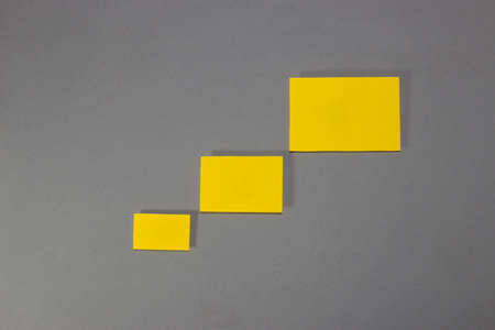 three (3) blank yellow papers of different sizes from smallest to largest arranged diagonally on a...