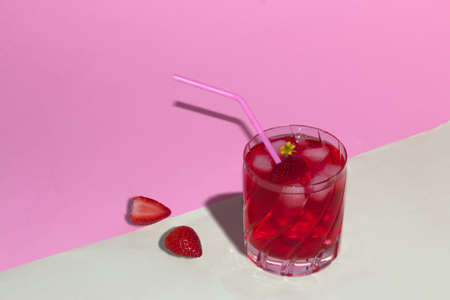 drinking glass cold strawberry juice, beautifully arranged with strawberry next to glass on a pastel pink-gray background, creative summer compositionの写真素材