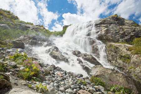 Beautiful waterfall. On a Sunny day the mountain stream flows among the forest . Panoramaの写真素材