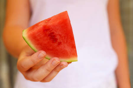 Slice of watermelon in female hand.