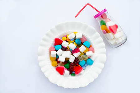 Colorful candys on a white plate. Unhealthy food and too much sugar concept.