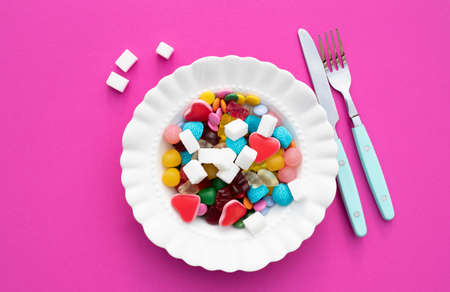 Colorful candys on a white plate. Unhealthy food and too much sugar concept.の写真素材