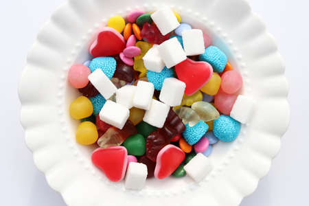 Colorful candys on a white plate. Unhealthy food and too much sugar concept.
