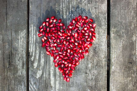 pomegranate macro seeds in heart shape on grey wooden backgroundの写真素材
