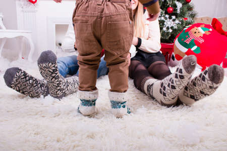 feeds of man woman and they child in knitted socks near christmas treeの写真素材
