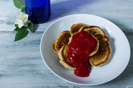 pancakes for brekfast near beautiful white flowers in blue bottle. jasmin. wooden grey background