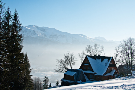 House in the snow. Photography in the mountains in winter. Beautiful blue sky and mountains in the snow. The road, Which roam the people.の写真素材