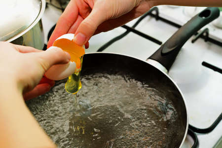 Breaking egg into the boiling waterの写真素材