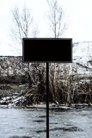 Blank billboard by the frozen riverの写真素材