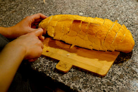Slicing loaf of bread on bread boardの写真素材