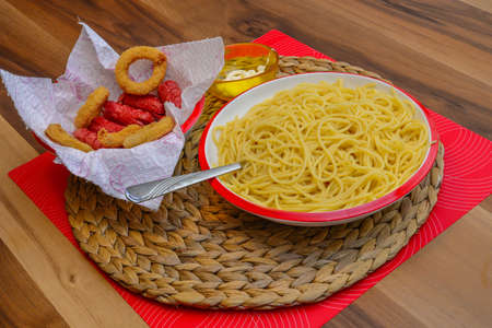 Macaroni pasta onion rings and sausage homemade serve on wood backgroundの写真素材
