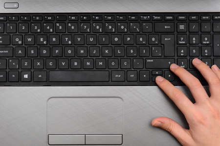 Laptop keyboard with woman hand on