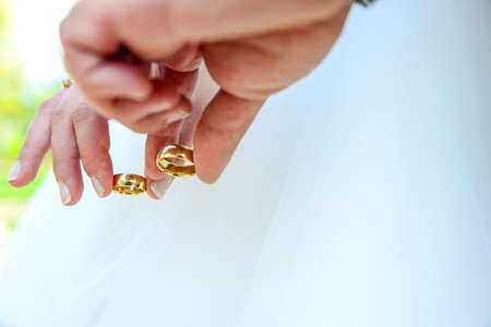 Bride and groom holding hands with engagement rings on their fingers close up view wedding shoot conceptの写真素材