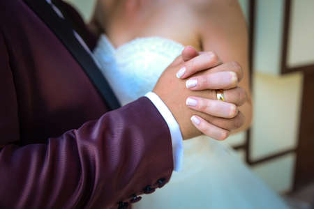 Bride and groom holding hands with engagement rings on their fingers close up view wedding shoot conceptの写真素材