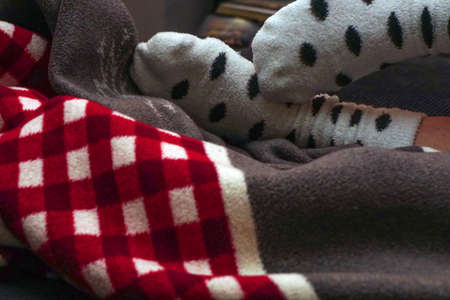 Red and white blanket and feet with white dotted socks chilling at home close up viewの写真素材