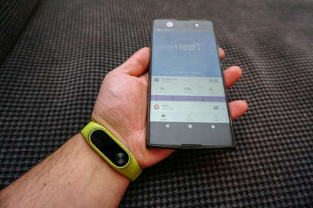 Smartphone and fitness activity tracker bracelet on the wrist close up view