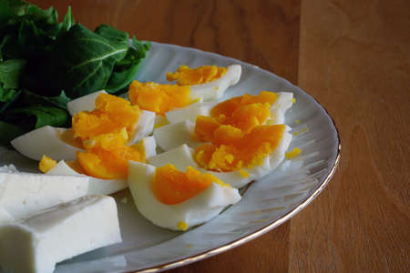 Coddled boiled eggs with season herbs cheese and olives on the white dish taken with natural lightの写真素材