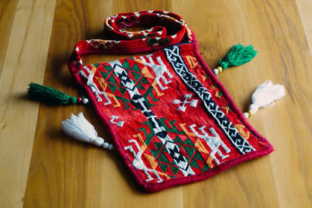 Ethnic patterned red saddlebag sack on wooden background close up viewの写真素材