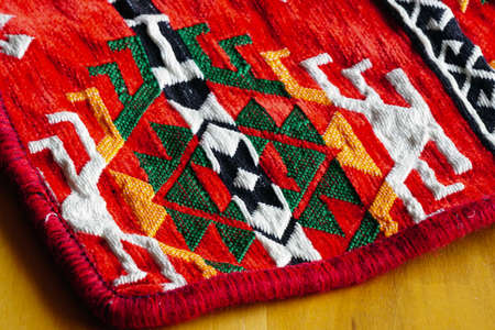Ethnic patterned red saddlebag sack on wooden background close up viewの写真素材