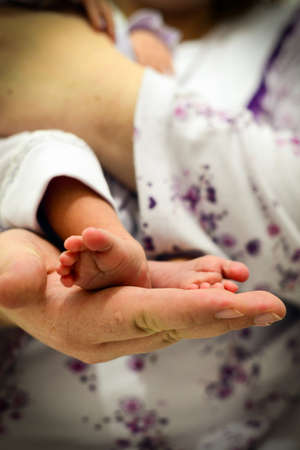 Newborn baby foot in mother hand close up view portrait imageの写真素材