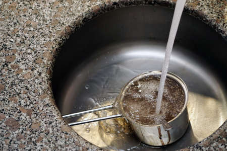 Hand washing the frypan in the lavaboの写真素材