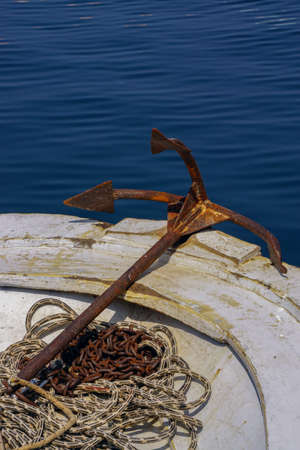 Rusted anchor attached to the rope on the boat portraitの写真素材