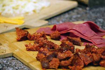 Chopped sausage and jambon on cutting board close up view preparation for the pizzaの写真素材