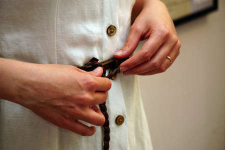 Woman trying on dress with hands on the beltの写真素材