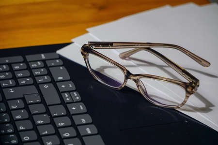 Glasses laptop keyboard and notes on wooden background business concept close up viewの写真素材