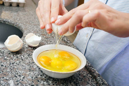 White eggs and woman hand preparation in kitchenの写真素材