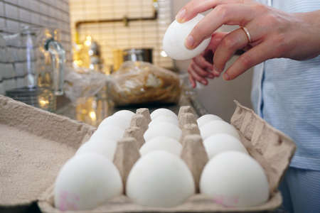 White eggs and woman hand preparation in kitchenの写真素材