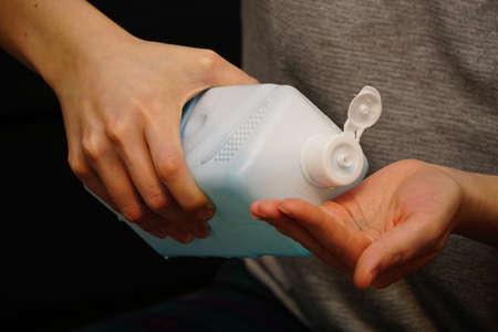 Woman pouring hand sanitizer disinfectant in her hand at home to avoid from corona virusesの写真素材