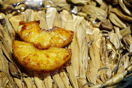 Grilled pineapple ananas with honey and cinnamon on straw mat texture backgroundの写真素材