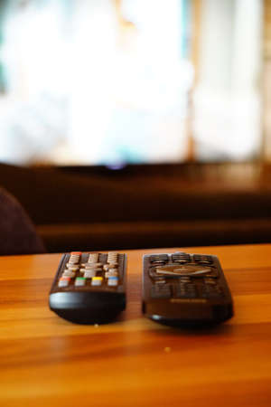 Two television remote controllers on wooden background image with shallow depth of fieldの写真素材