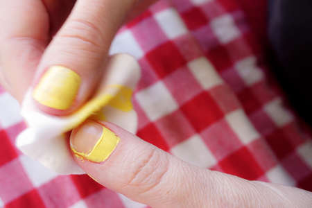 Woman removing nail polish on red table cloth background close up viewの写真素材