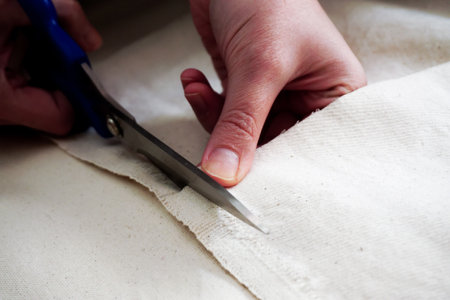 Woman measuring and cutting fabric at home close up viewの写真素材