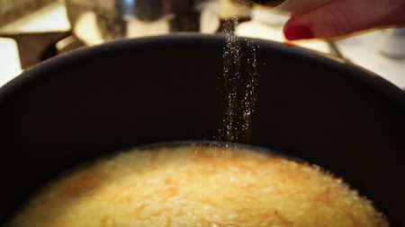 Salting down the cooking meal in the frypan close up viewの写真素材