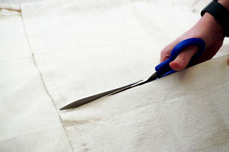Woman measuring and cutting fabric at home close up viewの写真素材