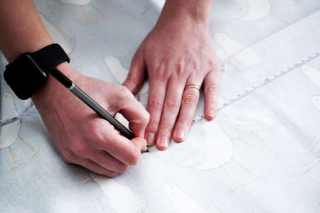 Woman measuring and cutting fabric at home close up viewの写真素材