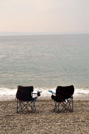 Collapsible beach chairs on pebble stone beachの写真素材